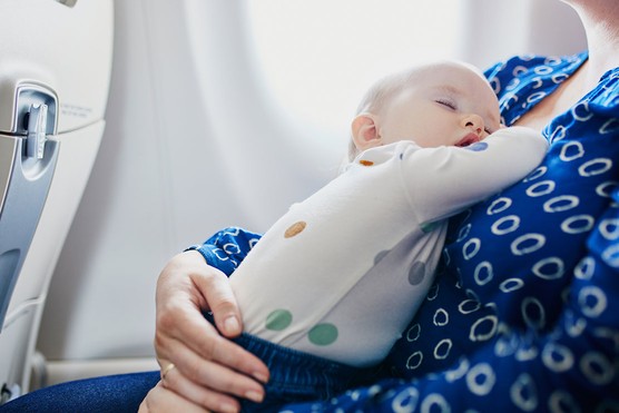 baby on plane asleep on mother's chest