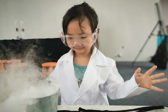 A young girl wearing safety goggle conducting a science experience