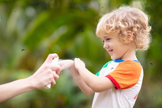 young boy being sprayed with insect repellant