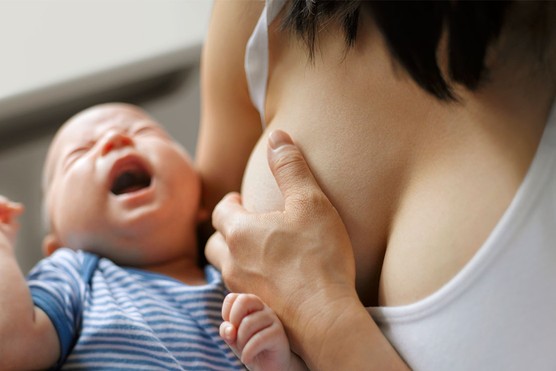 breastfeeding mother holding painful breast with sore nipple