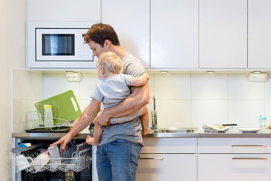 dad holding baby and putting feeding bottle in dishwasher