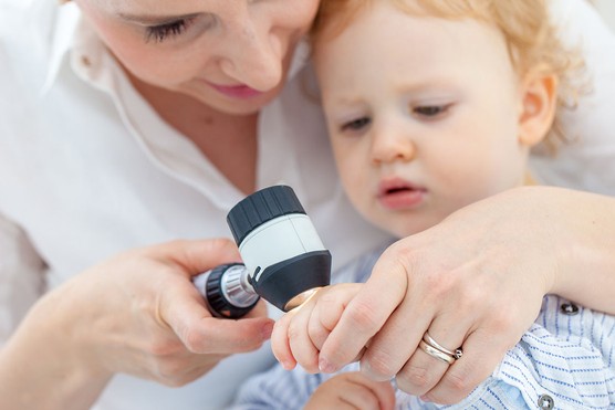 a dermatologist checking a little boy's moles at a clinic