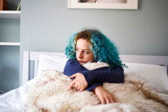 Young woman with blue hair looking sad depressed and alone in bed