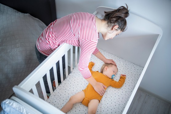 Caring young mother putting her baby boy for his nap.