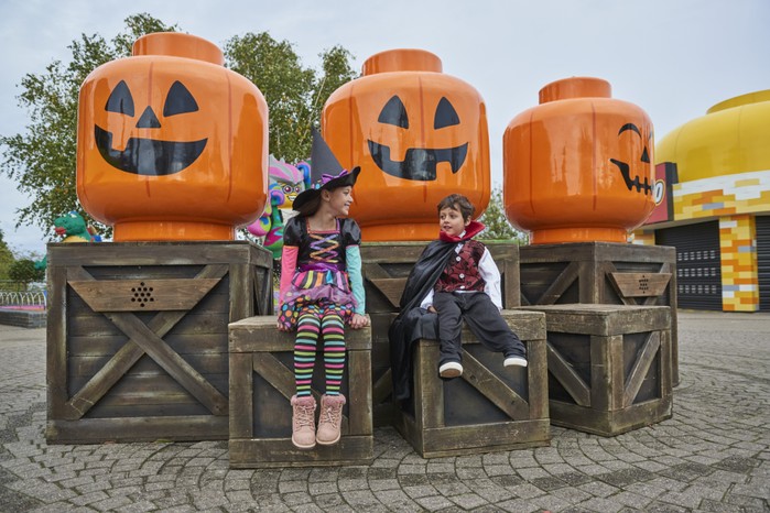 Children smiling in front of large LEGO pumpkins