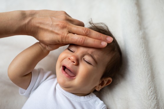 parent feeling forehead of baby with fever