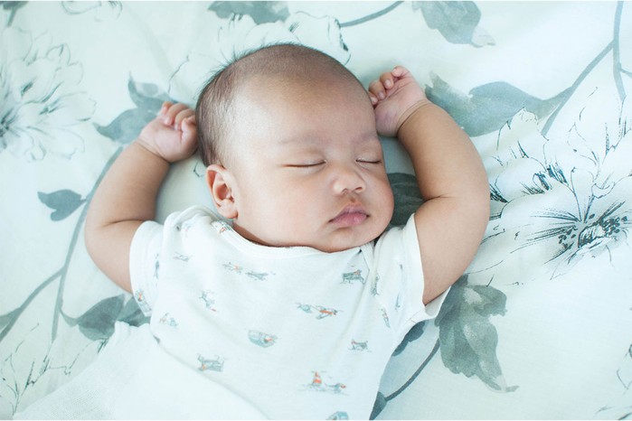 baby boy lying on a sheet decorated with leaves