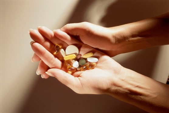 close up of a woman's hands holding a selection of supplements and vitamins