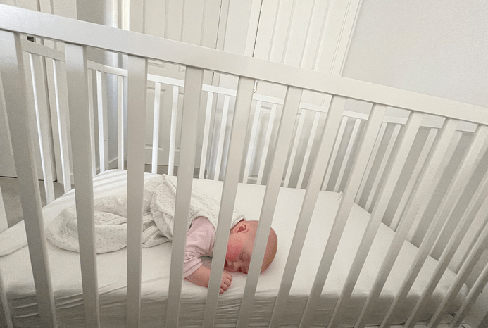 Baby lying in Ickle Bubba Hartley Classic Cot 2